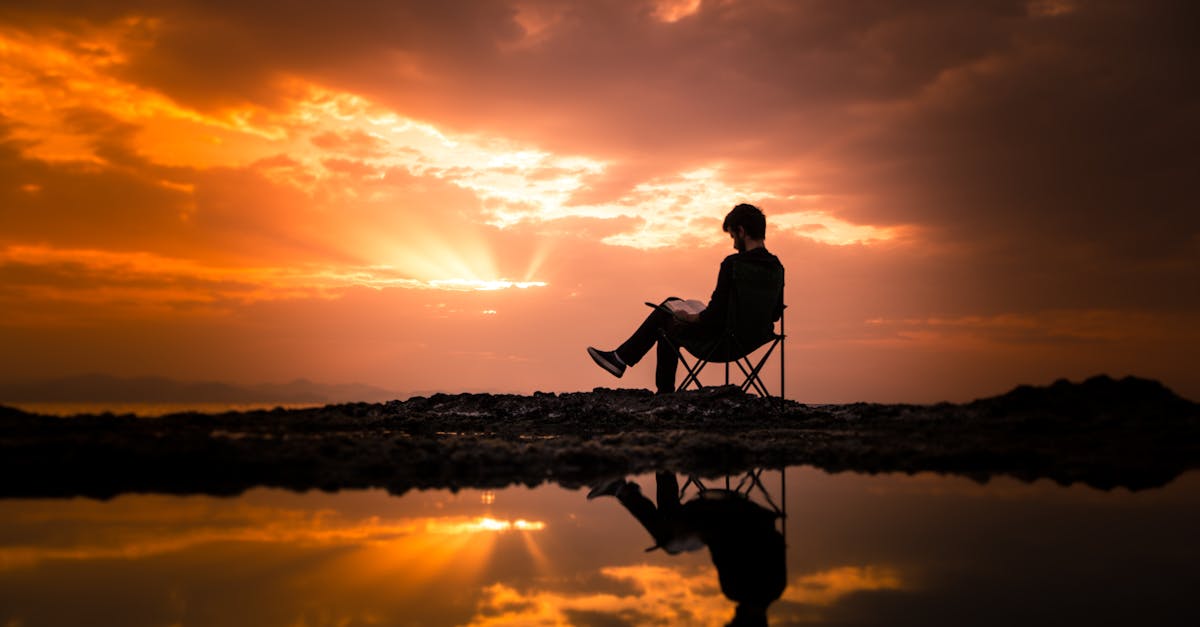 A person reading on a chair by a reflecting pond at sunset in Korgan, Turkey.